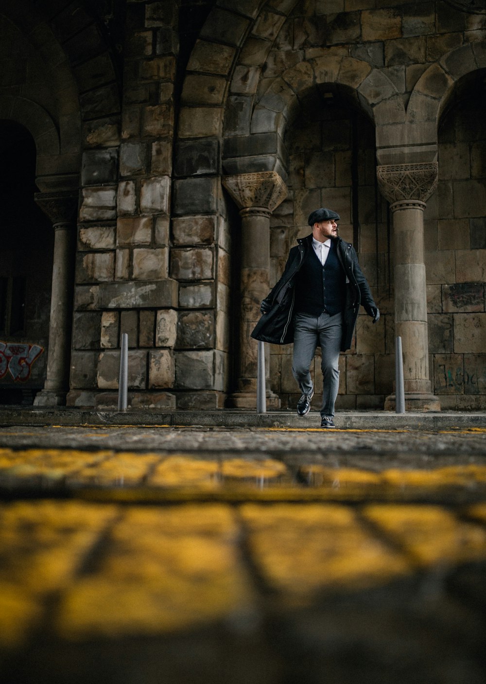 man in black suit standing on yellow concrete floor