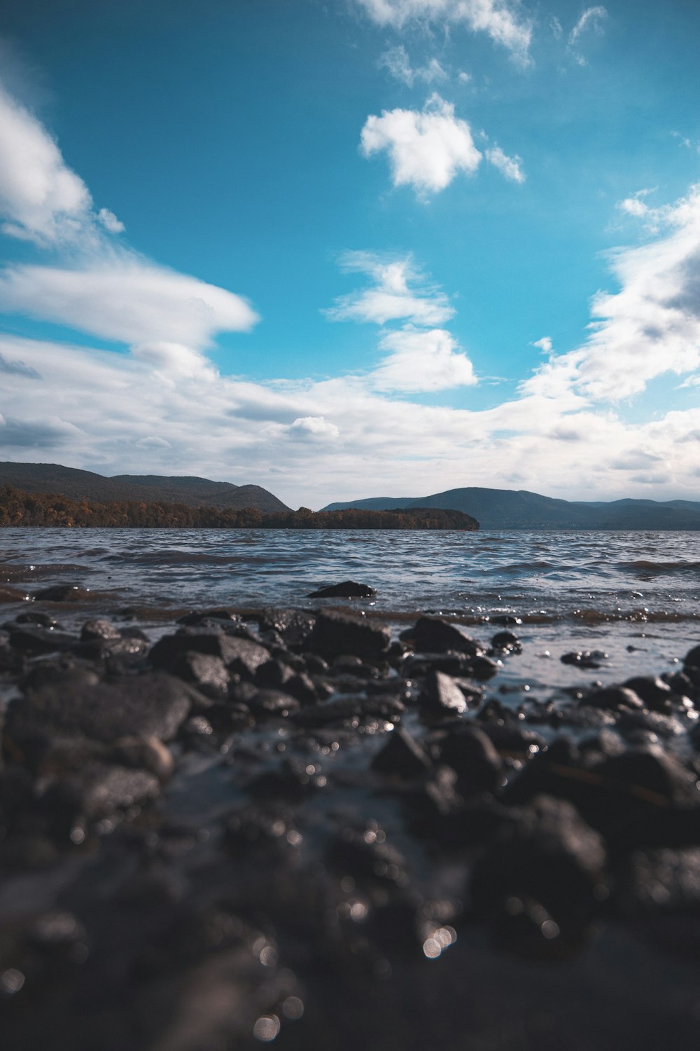 body of water near mountain under blue sky during daytime