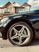 A friendly technician fitting a tyre on a car parked outside a suburban home