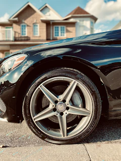 A friendly technician fitting a tyre on a sleek car parked on a quiet suburban street