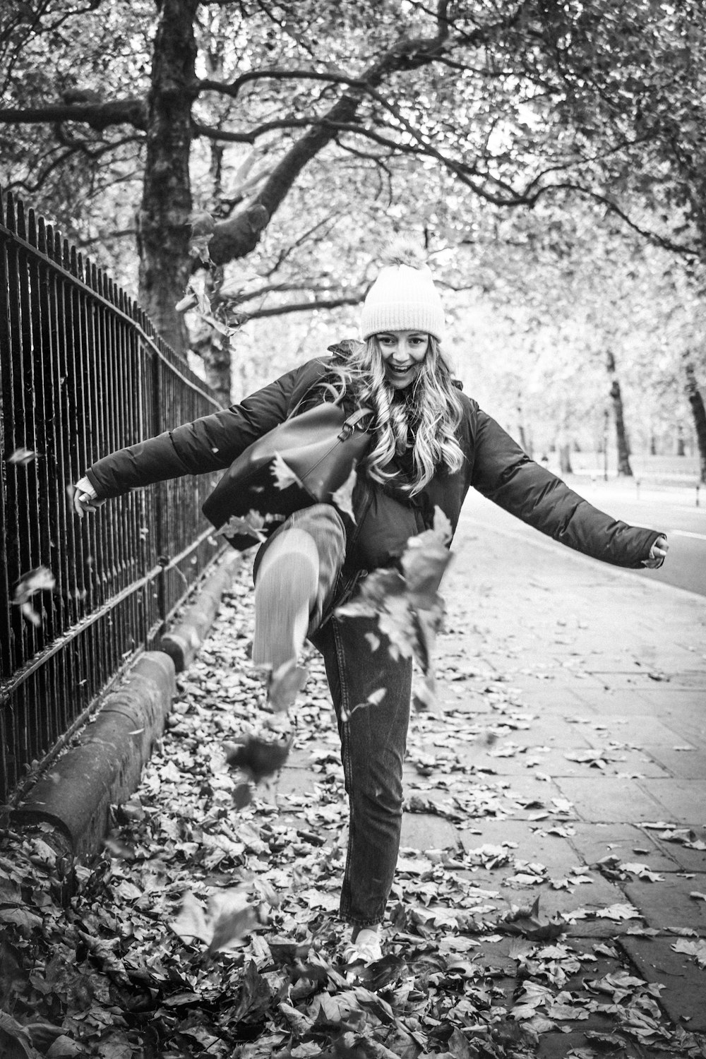 grayscale photo of woman in black jacket and pants standing on pathway