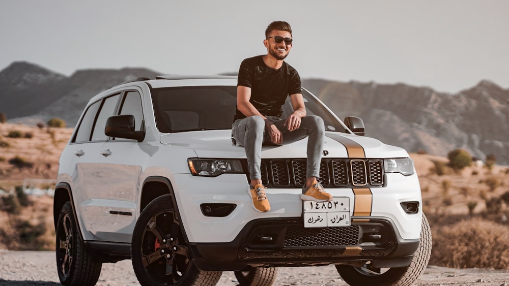 man in black crew neck t-shirt sitting on white ford suv