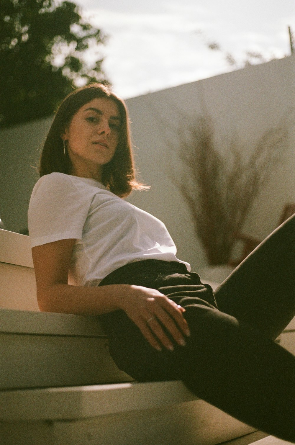 woman in white t-shirt and black pants sitting on white bench