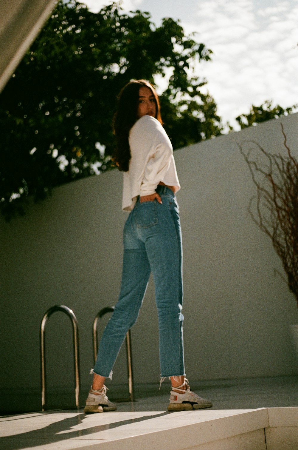 woman in white long sleeve shirt and blue denim jeans standing on ladder