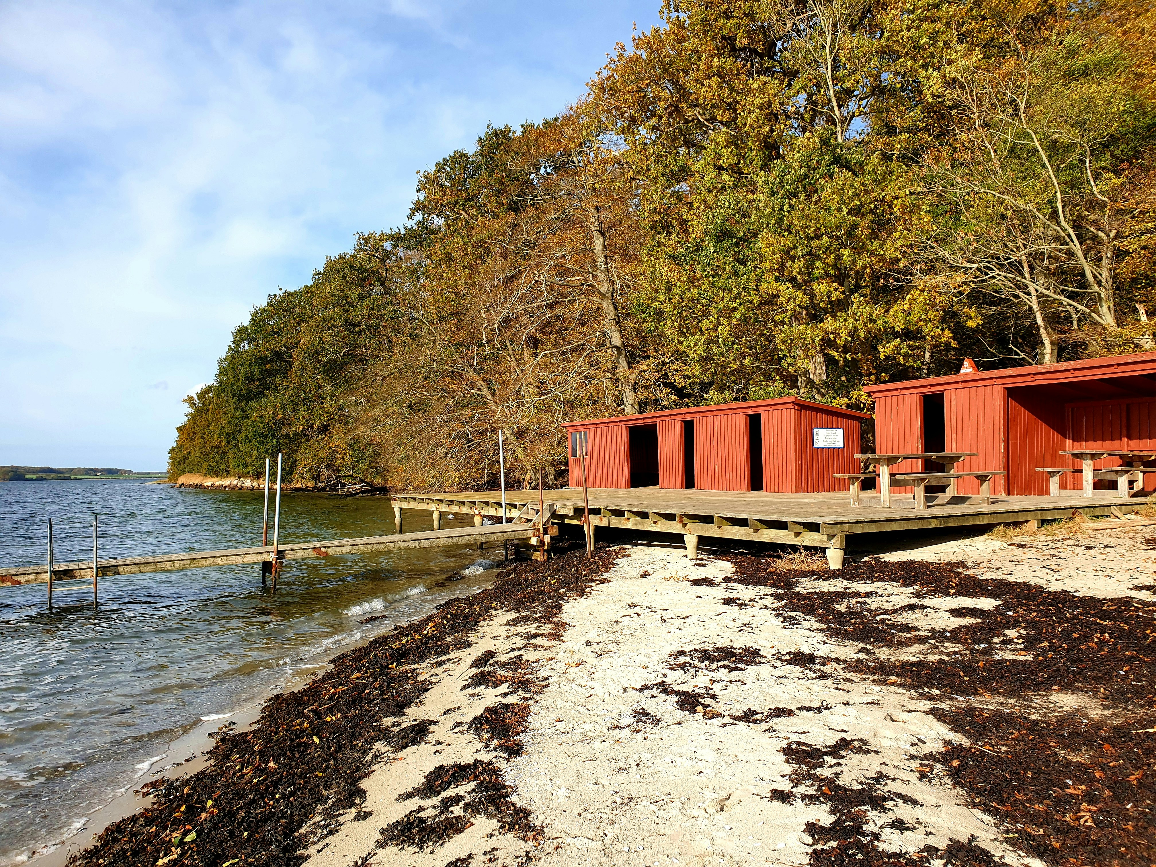 Red and white wooden house near body of water during daytime photo ...