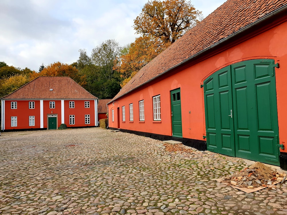 green and red wooden houses near green trees under white clouds during daytime