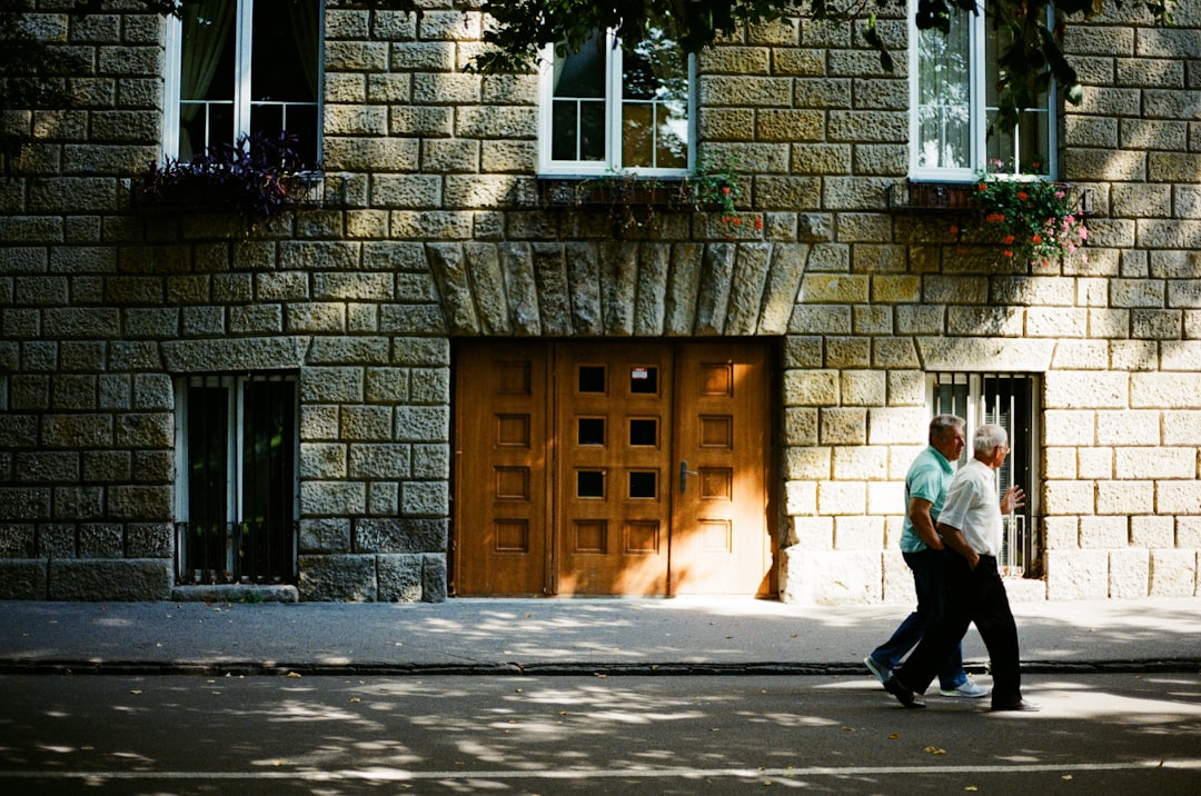 man in white dress shirt and black pants walking on sidewalk during daytime