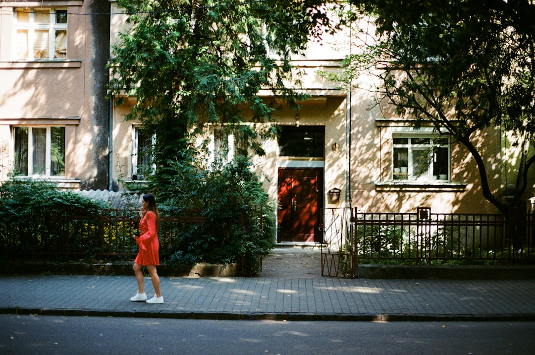 woman in red dress walking on sidewalk during daytime