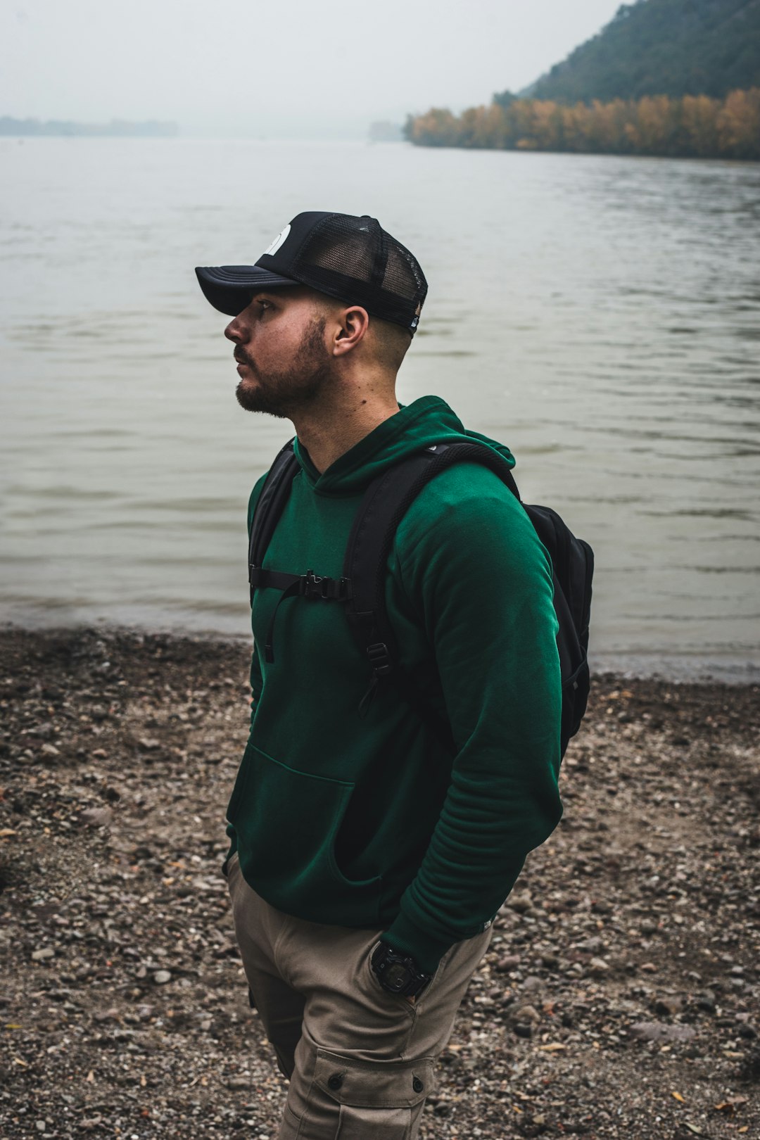 man in green jacket standing near body of water during daytime