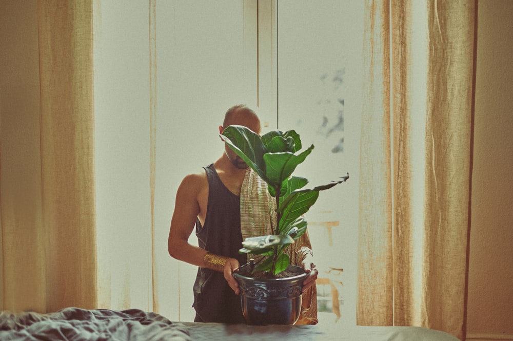 woman in black tank top holding green plant