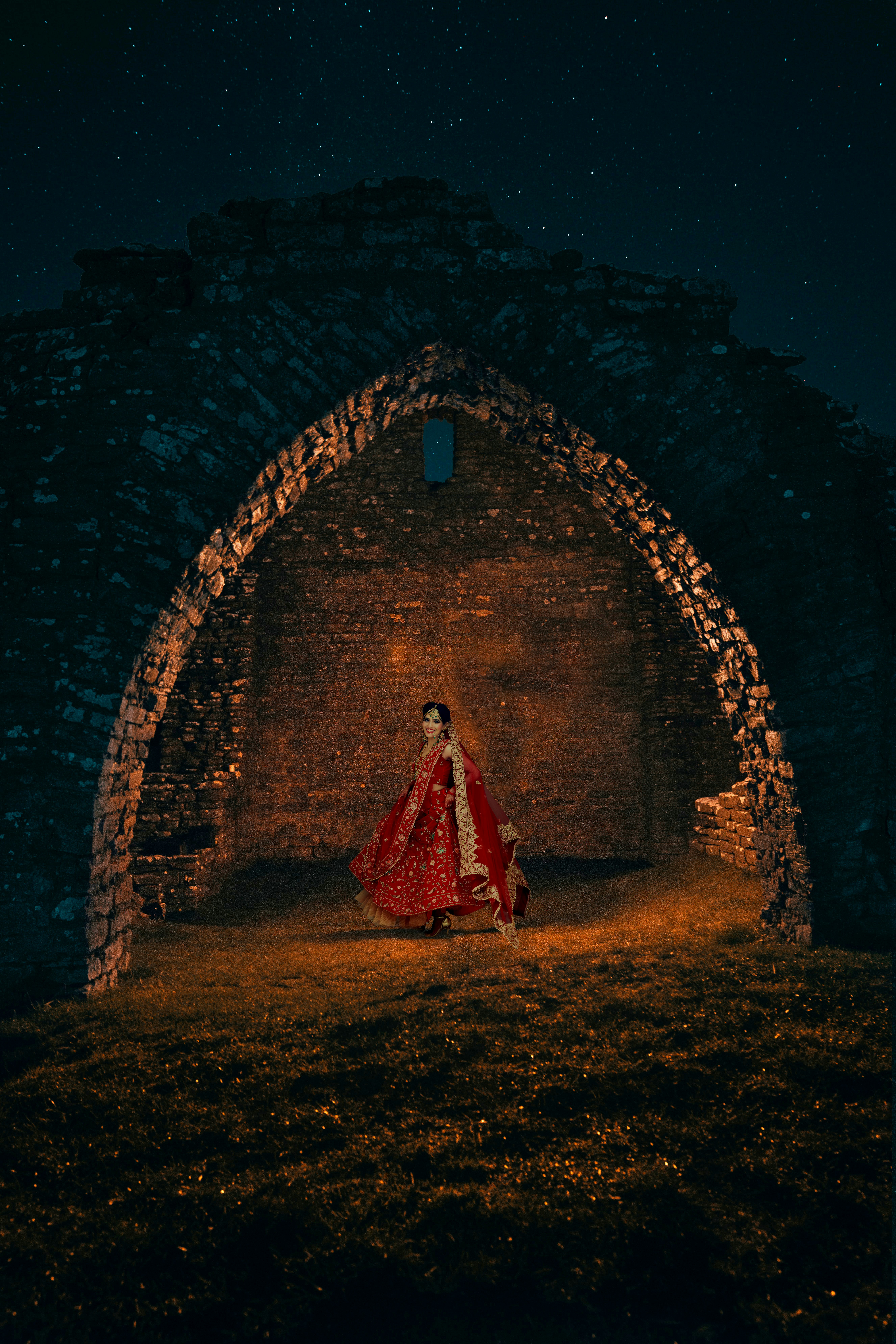 a woman in a red and white dress standing in a stone archway