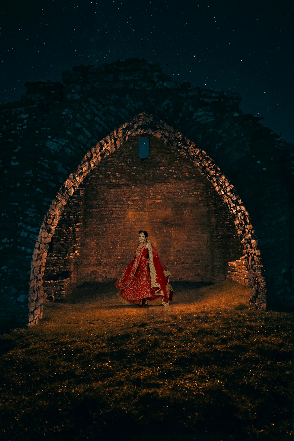 a woman in a red and white dress standing in a stone archway