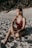 woman in red and black floral bikini sitting on sand during daytime