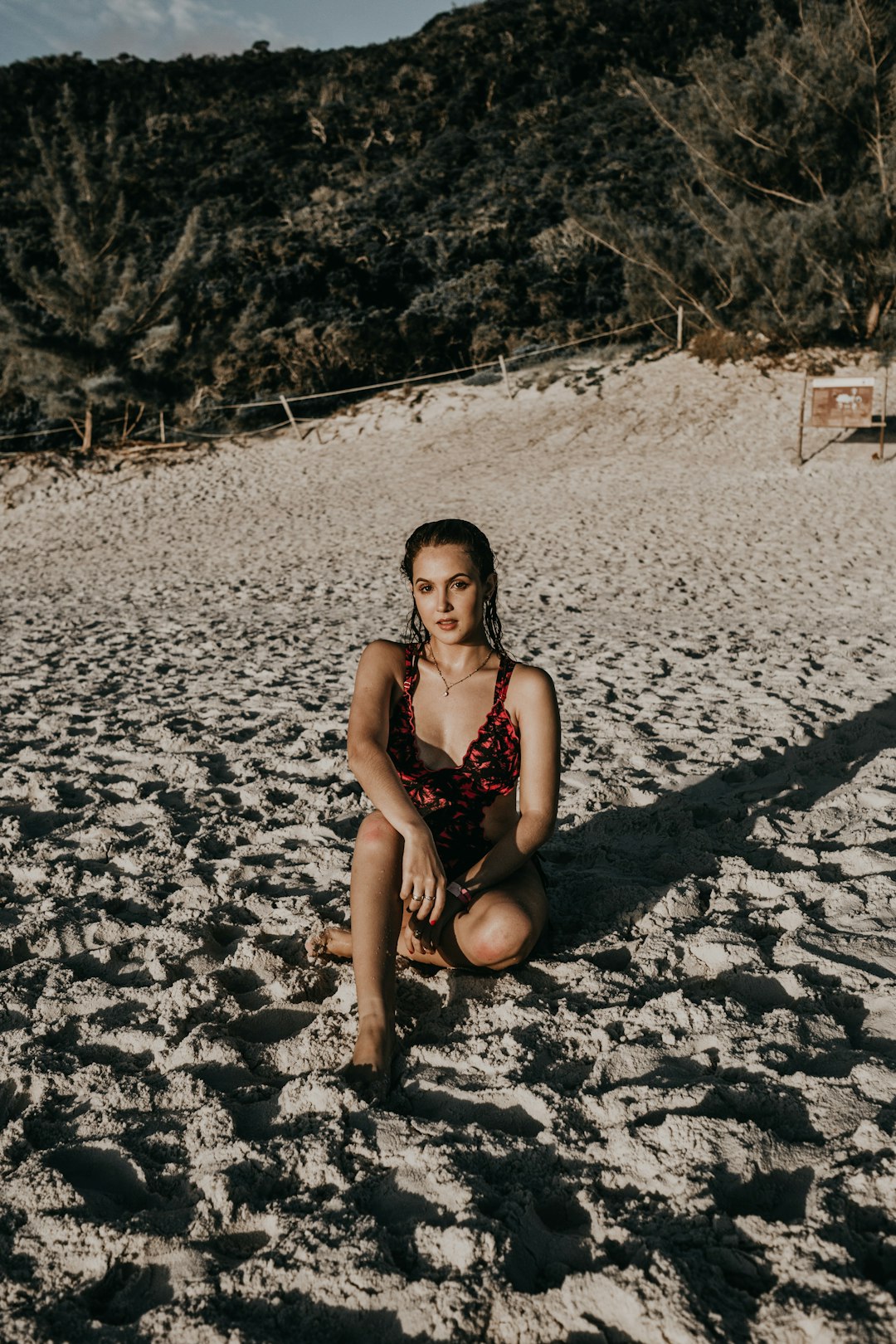 woman in black bikini sitting on white sand during daytime