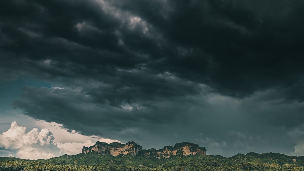 green and brown mountains under gray clouds