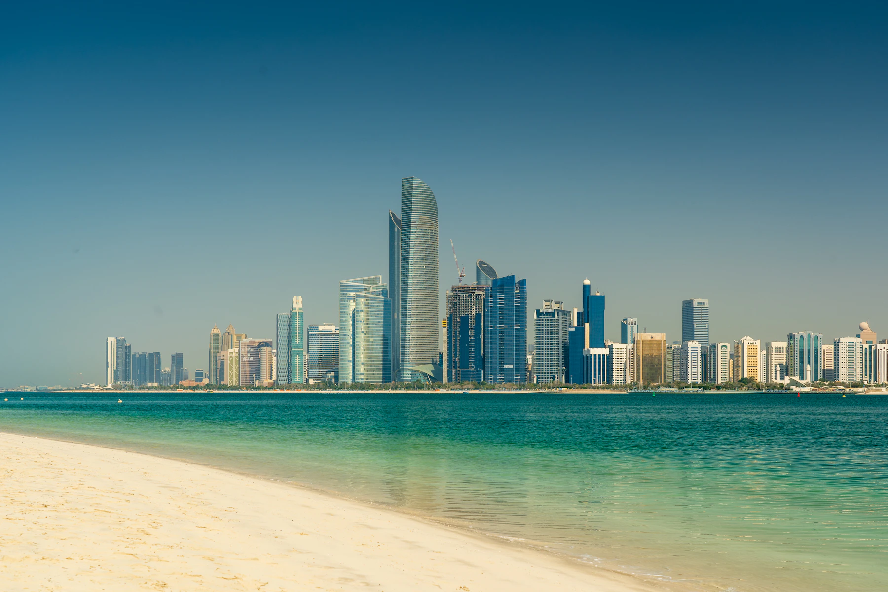 Abu Dhabi skyline rising across the calm blue water of the Arabian Gulf