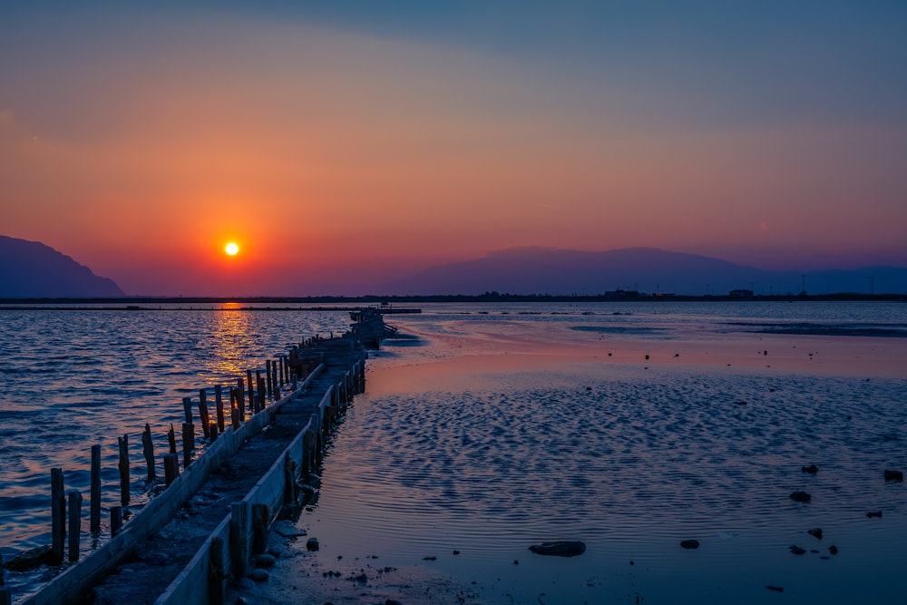 brown wooden dock on beach during sunset