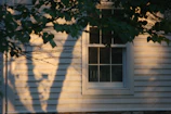 Sunlight casting shadows on the cottage’s muted brown exterior walls.