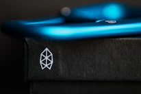 Close-up of a minimalist black and white logo sketch with electric blue highlights on a designer’s desk.