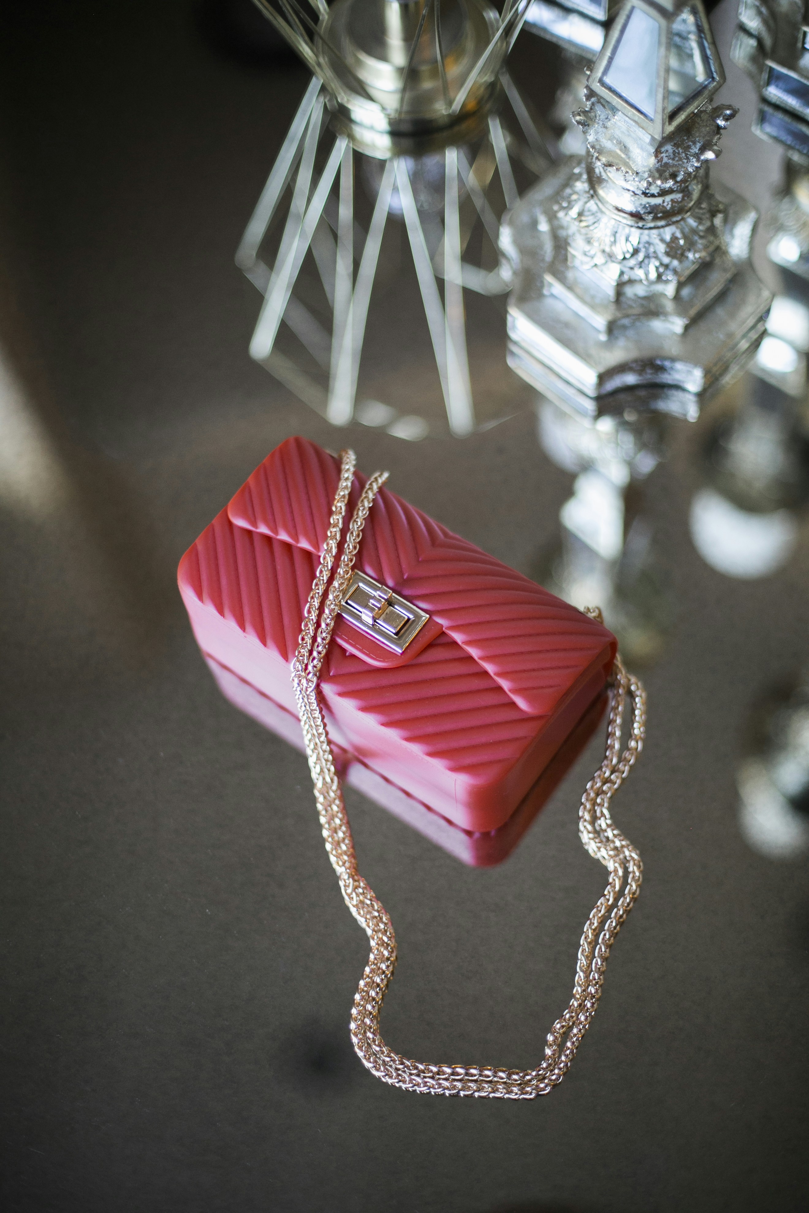 A red purse sits on a reflective surface.