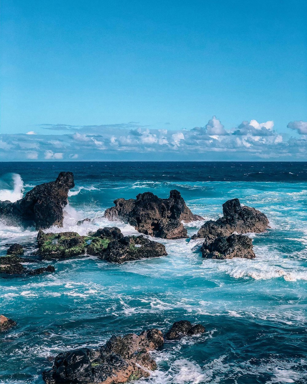 brown rock formation on sea under blue sky during daytime