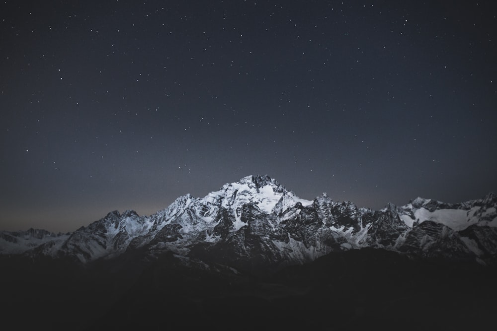 snow covered mountain under blue sky during night time