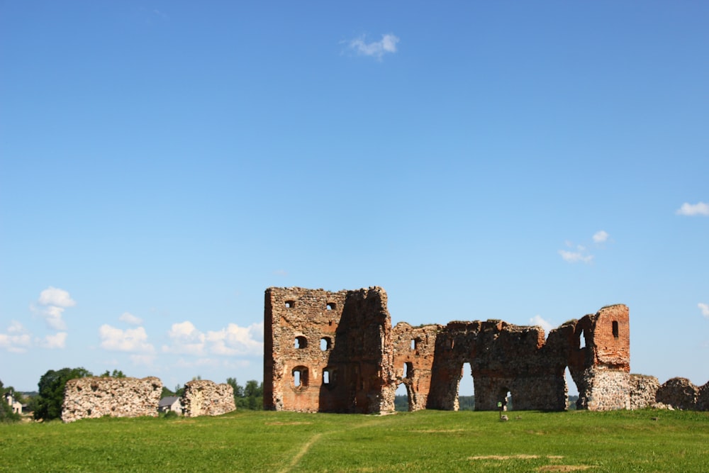 brown brick building on green grass field under blue sky during daytime