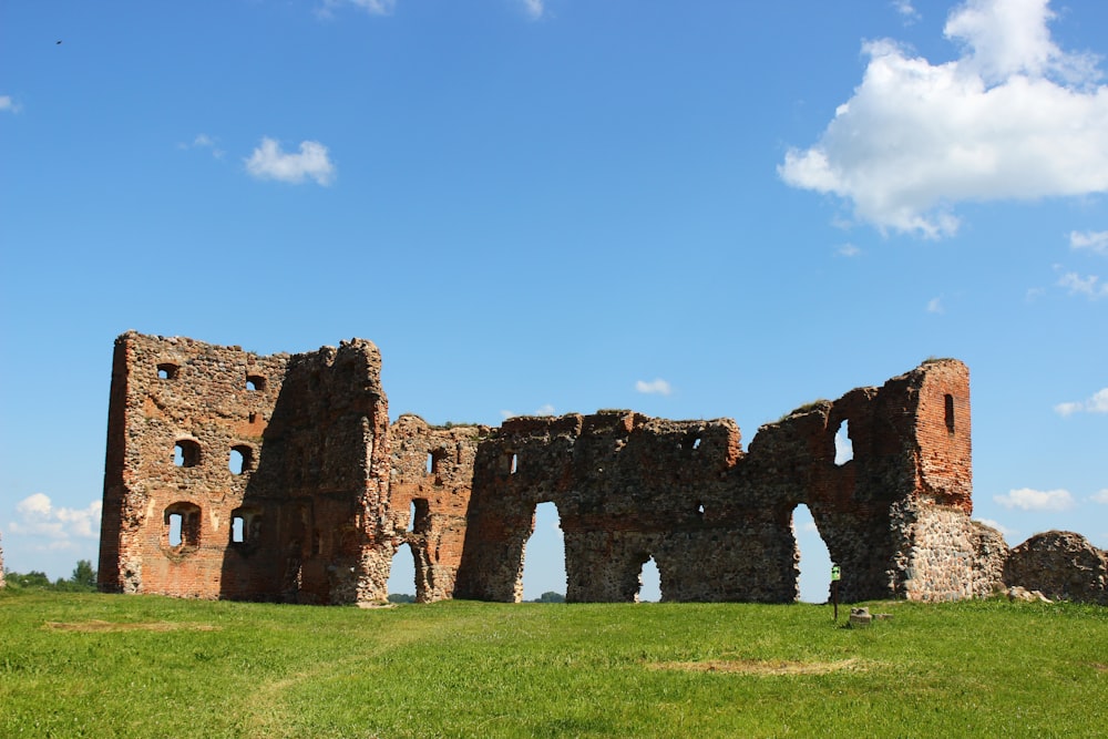 edificio in mattoni marroni sul campo di erba verde sotto il cielo blu durante il giorno