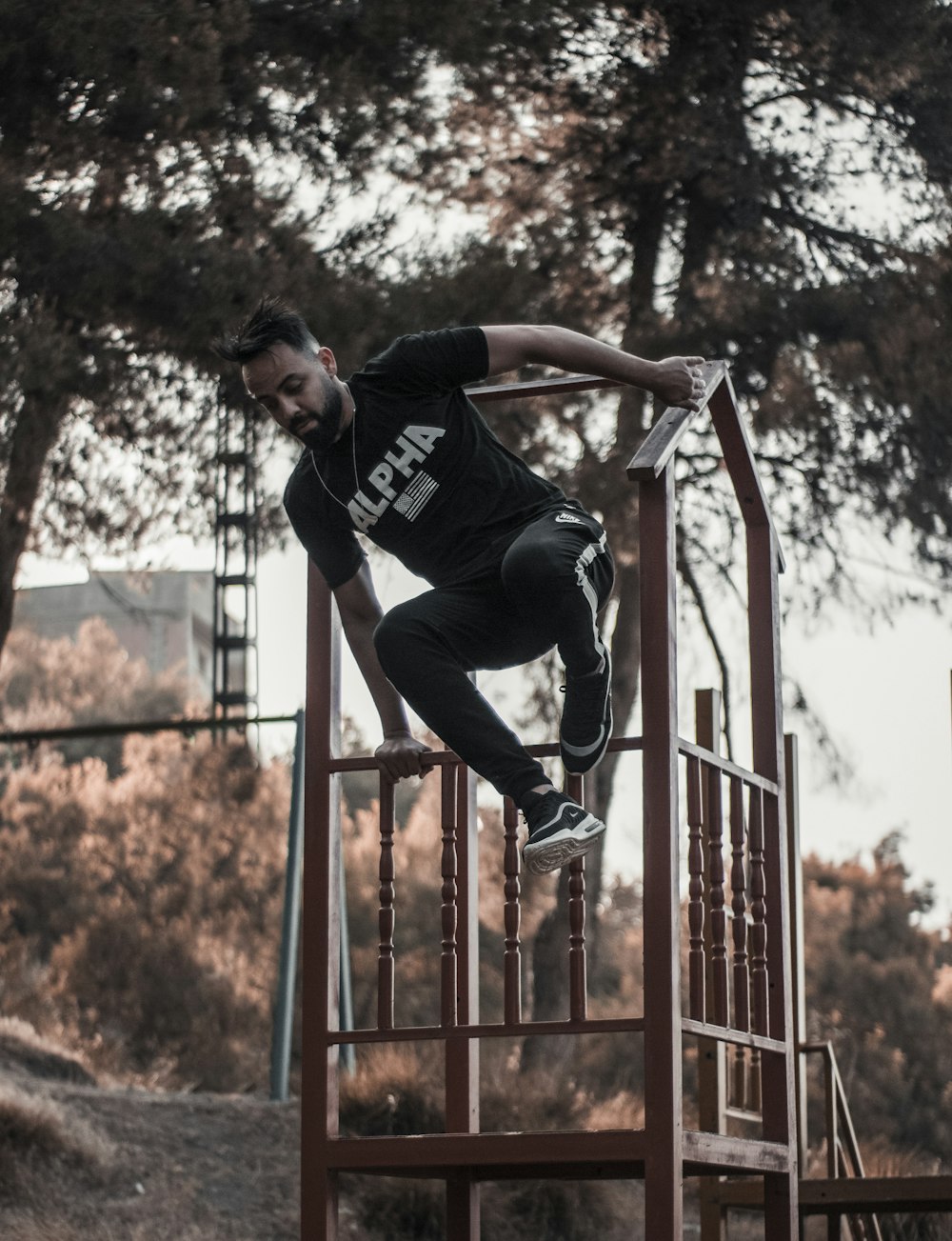 man in black t-shirt and black pants jumping on red metal railings