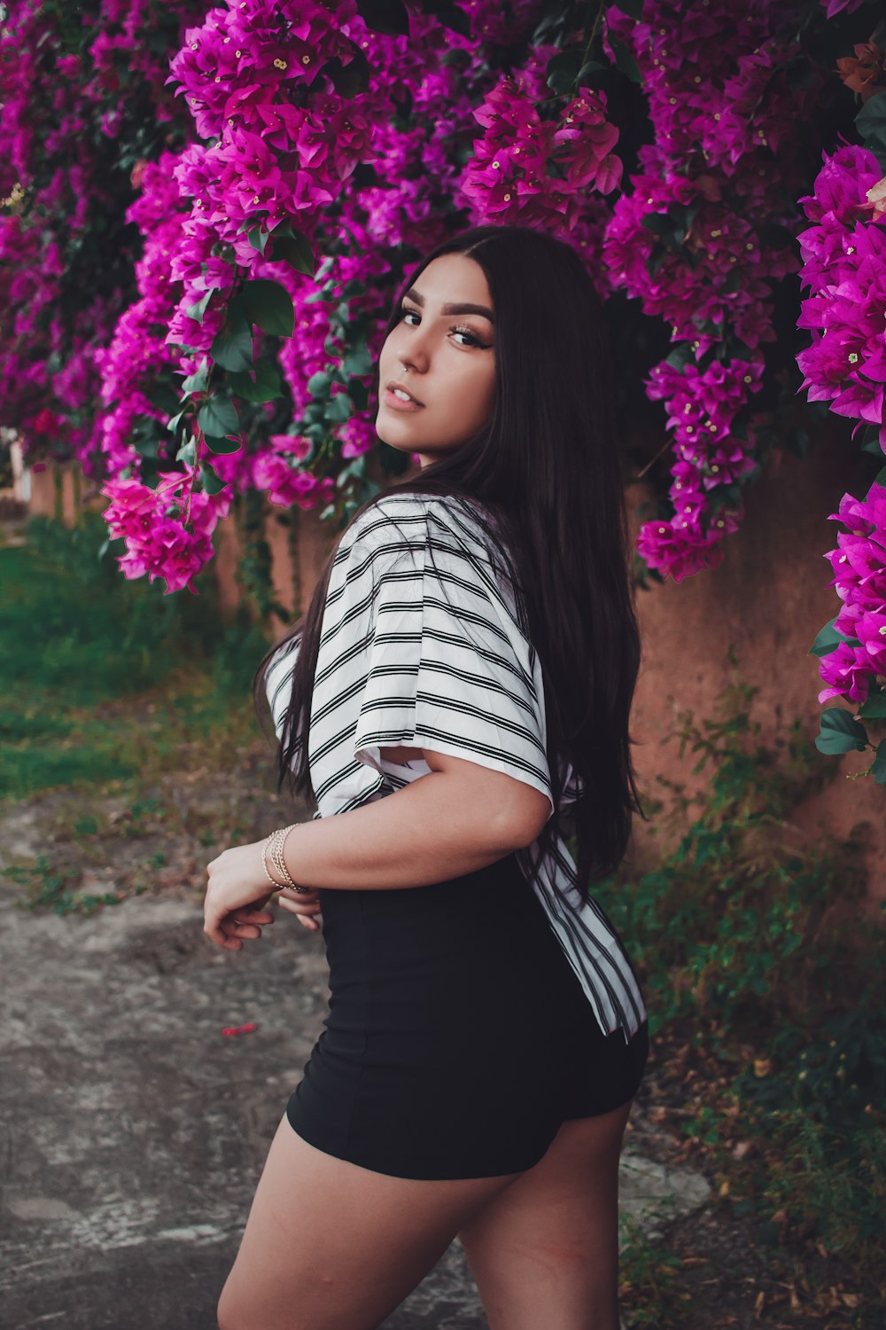 woman in black and white striped shirt standing near purple flowers