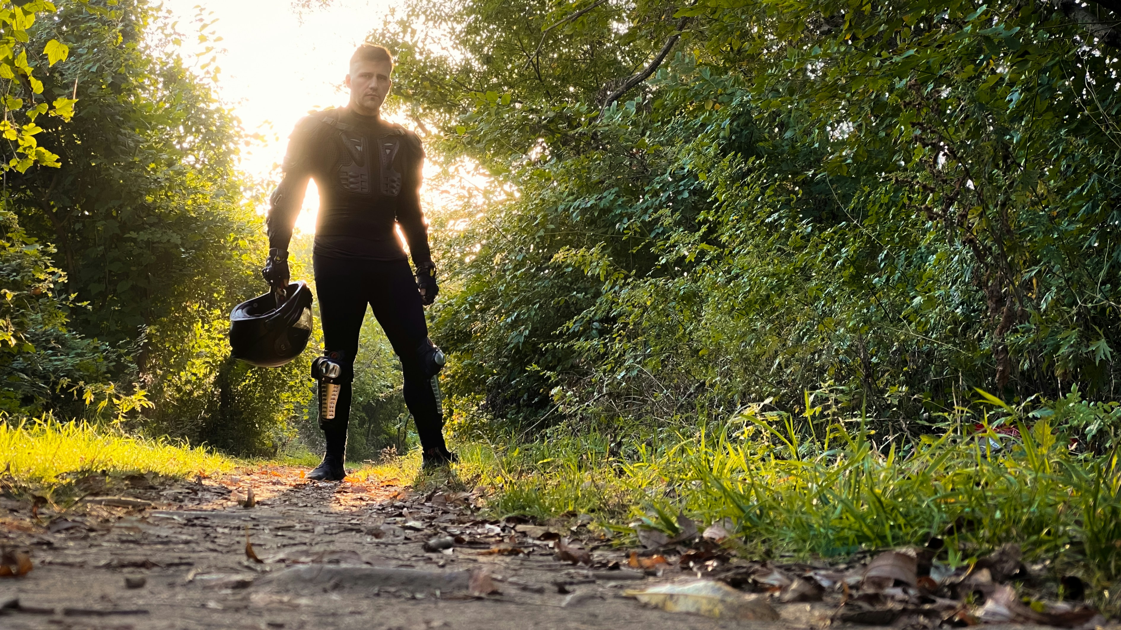 man in black pants carrying black backpack walking on dirt road during daytime