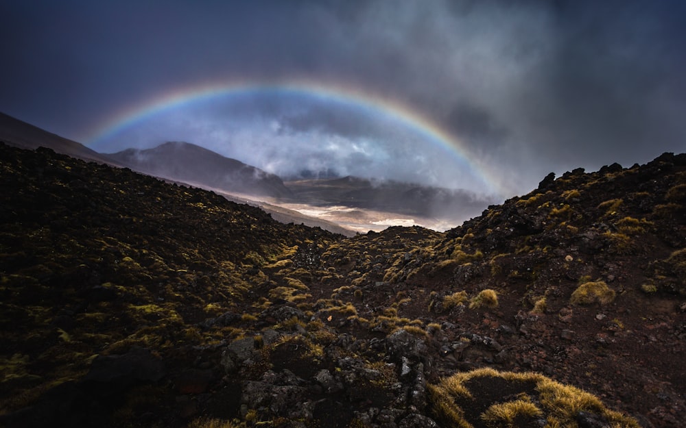 rainbow over brown and green mountain