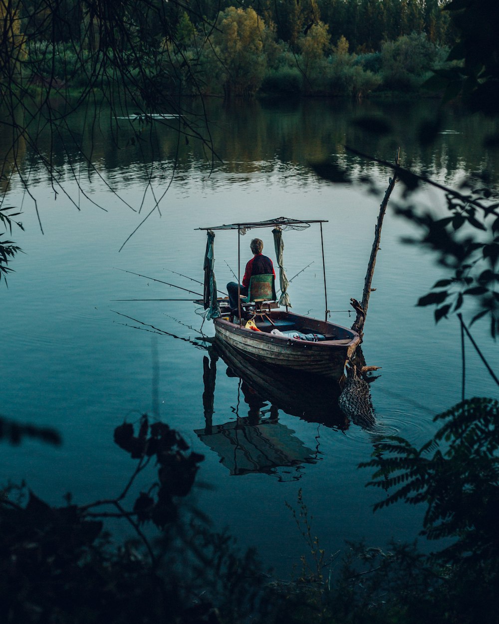 man in blue shirt riding on white and blue boat on lake during daytime