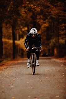 A cyclist wearing durable, skin-friendly gloves while riding through an autumn park