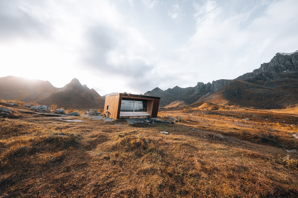 brown wooden house on brown field under white cloudy sky during daytime