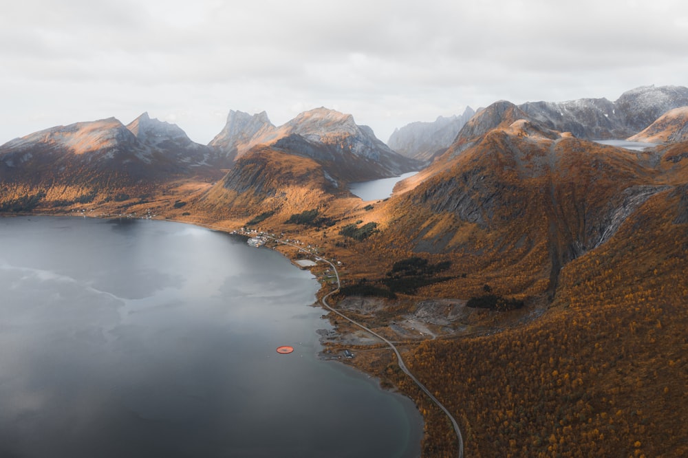 brown and green mountains beside lake under white clouds during daytime