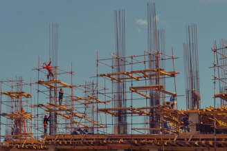 Hands of workers collaborating on a construction site under a clear sky.