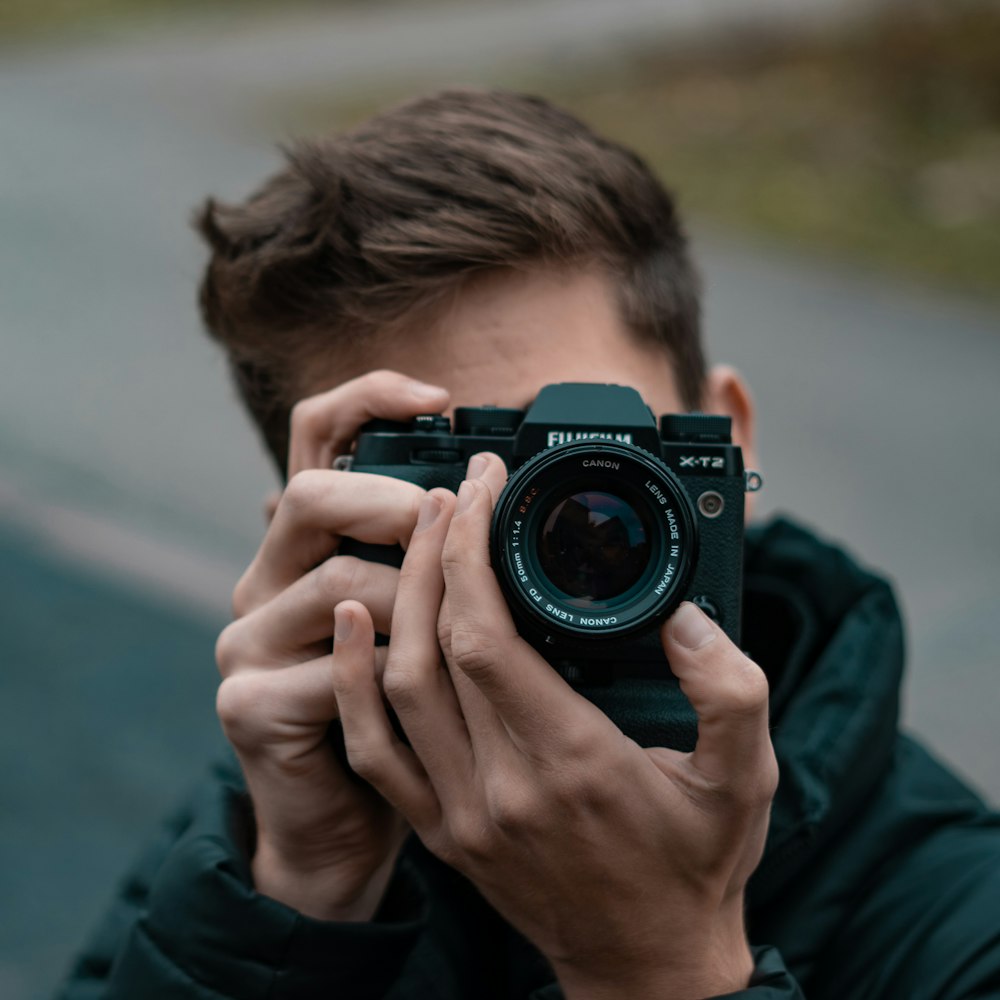 Mann im blauen Langarmshirt mit schwarzer Nikon DSLR-Kamera