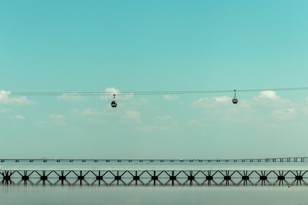 birds flying over bridge under blue sky during daytime