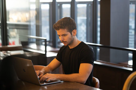 A professional working on a laptop with international landmarks behind.