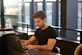 Photo of a confident man working on a laptop in a modern workspace.
