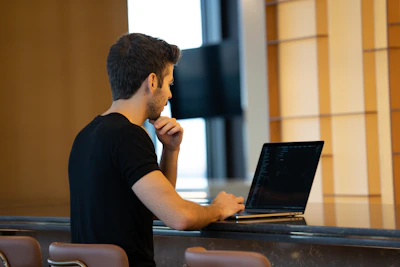 Close-up of a focused man working on a laptop in a cozy home office.