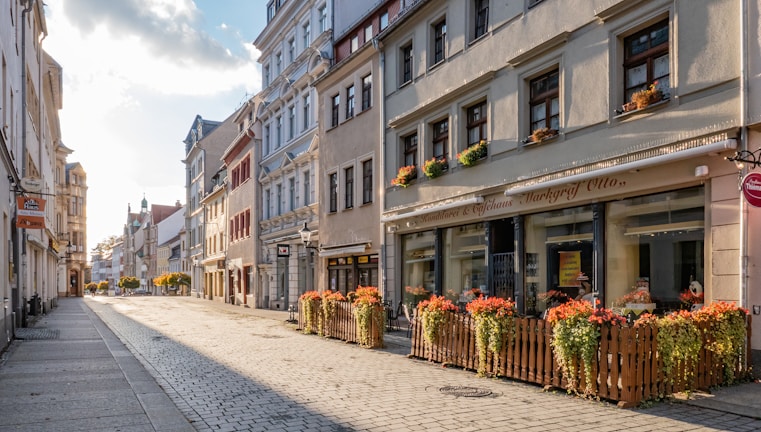 A quiet street in a small town lined with vintage shops and blooming flowers.