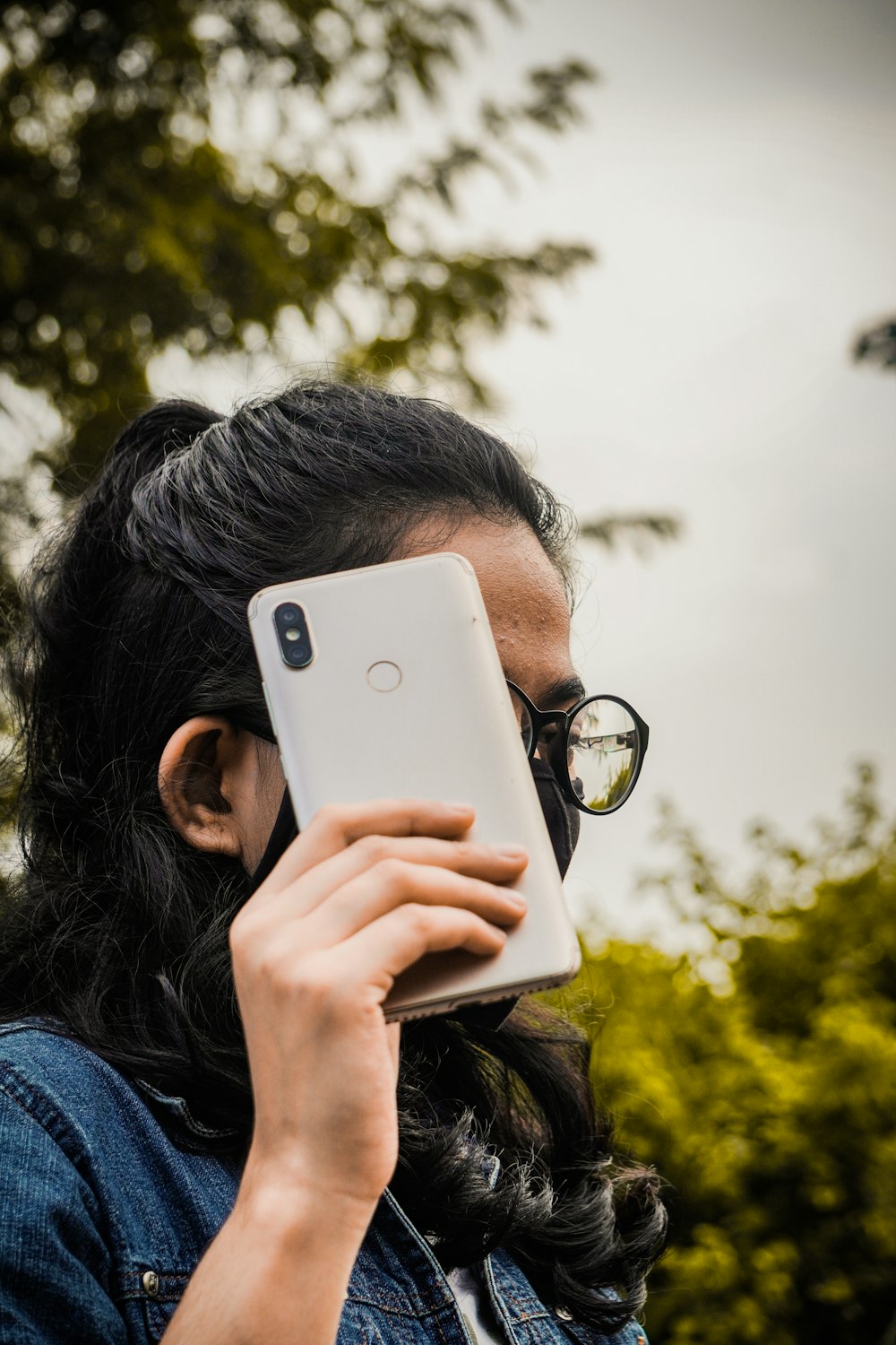 woman in blue denim jacket holding silver iphone 6