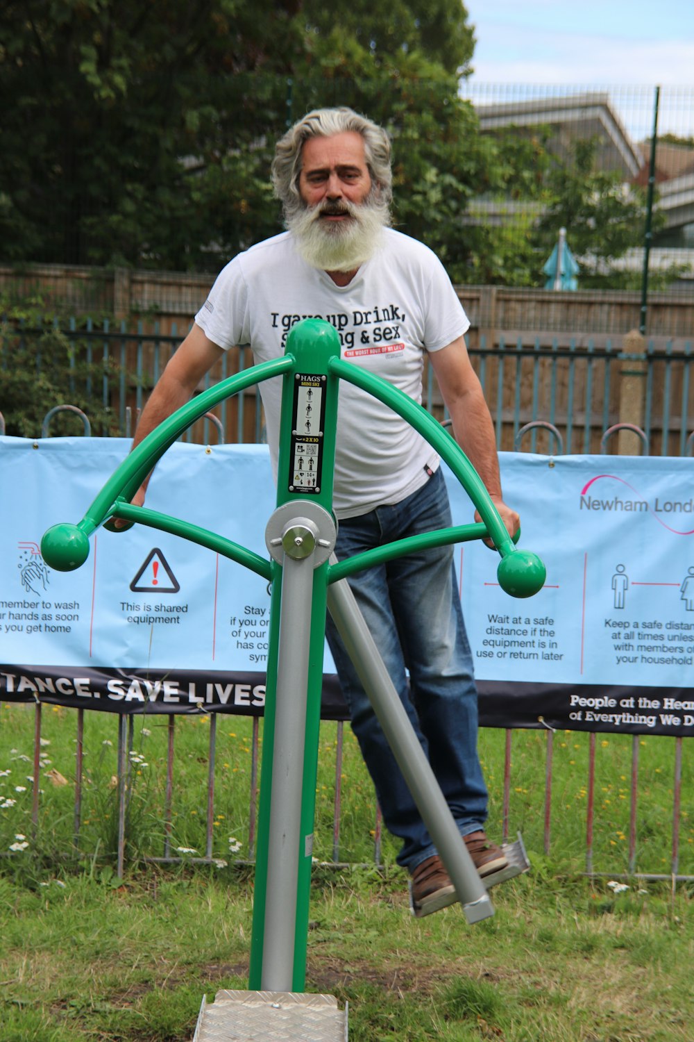 man in white crew neck t-shirt standing on blue metal railings during daytime