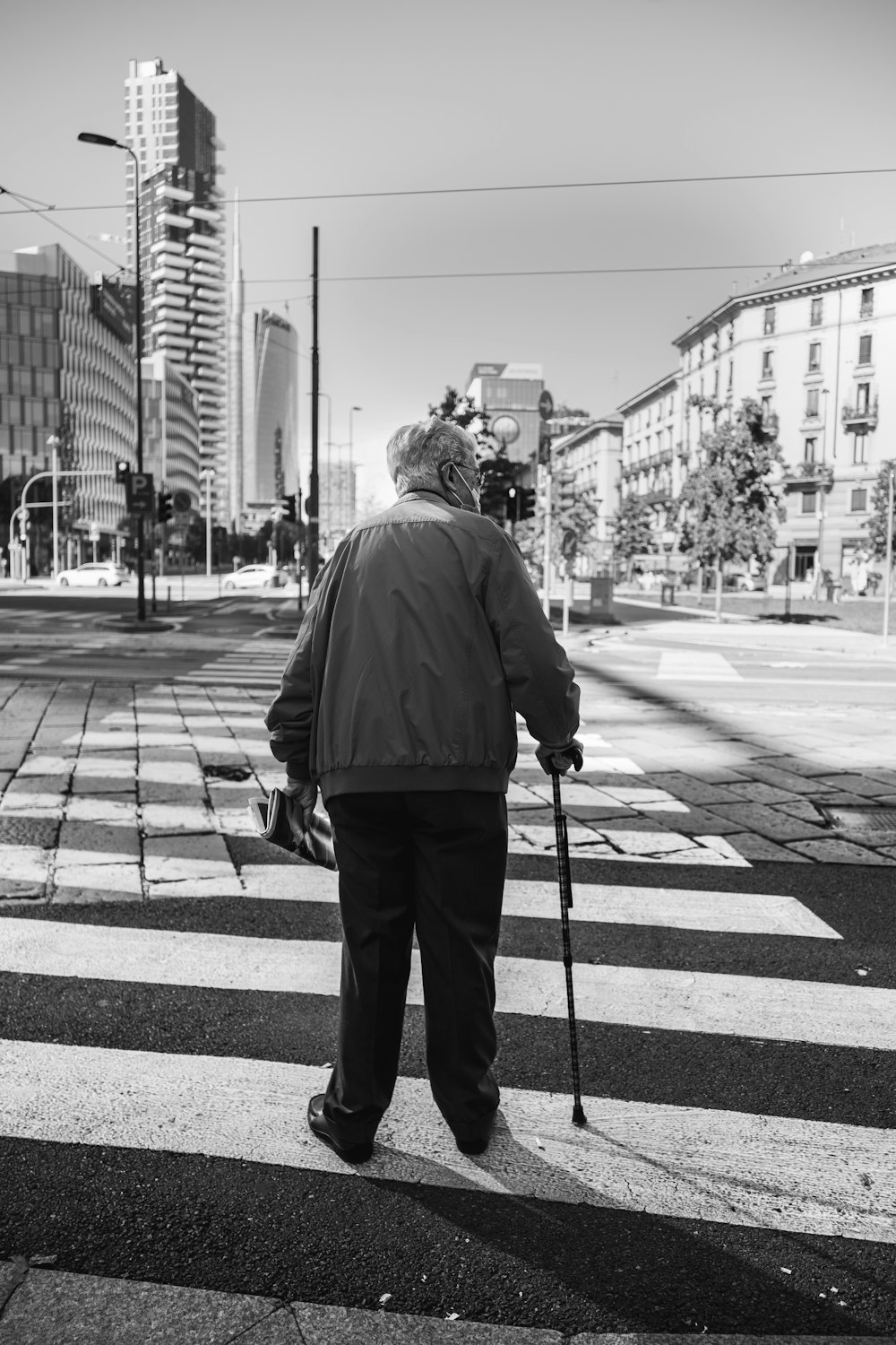 man in black jacket and pants standing on sidewalk during daytime