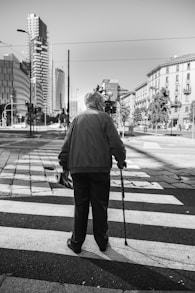 man in black jacket and pants standing on sidewalk during daytime