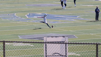 Close-up of a football player kicking the ball with intense focus on the field