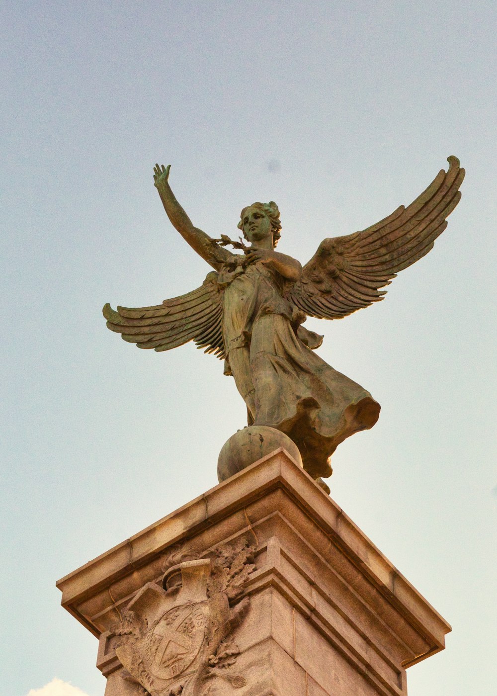 man holding book statue under blue sky during daytime