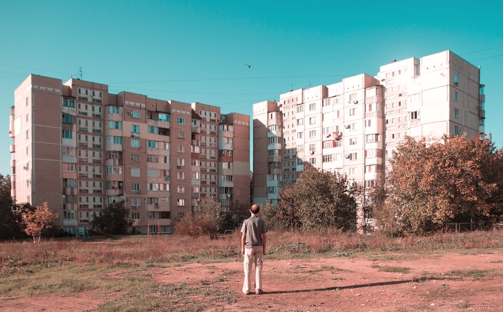 man in white shirt standing in front of white concrete building during daytime